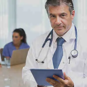 Smiling doctor with tablet at a meeting